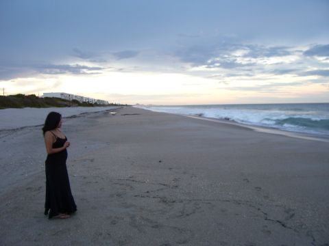 1994 Ford Probe - A woman stands on a sandy beach, looking out at the ocean waves under a cloudy sky.