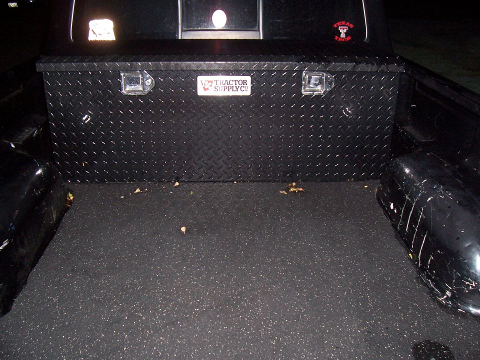 Black Tractor Supply diamond-plate truck bed toolbox mounted in pickup bed at night