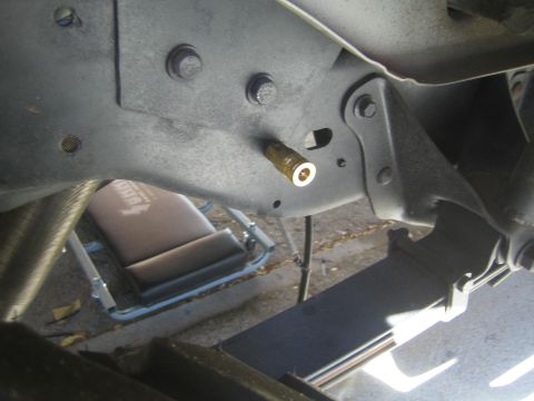 1990 Ford Bronco - Close undercarriage view of a vehicle's frame bracket with bolt holes and a protruding brass fitting.