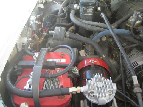 1990 Ford Bronco - engine bay showing a red Optima battery beside a red ExtremeAire air compressor with a finned cylinder.