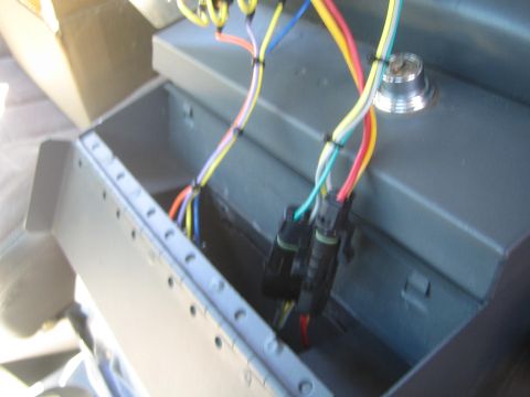 1990 Ford Bronco - gray painted sheet-metal compartment with bundled colored wires feeding into a black weatherproof connector.