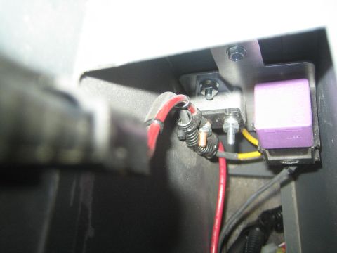 1990 Ford Bronco - Close-up of a black compartment with a red battery cable, yellow wire and a purple relay mounted to a bracket.