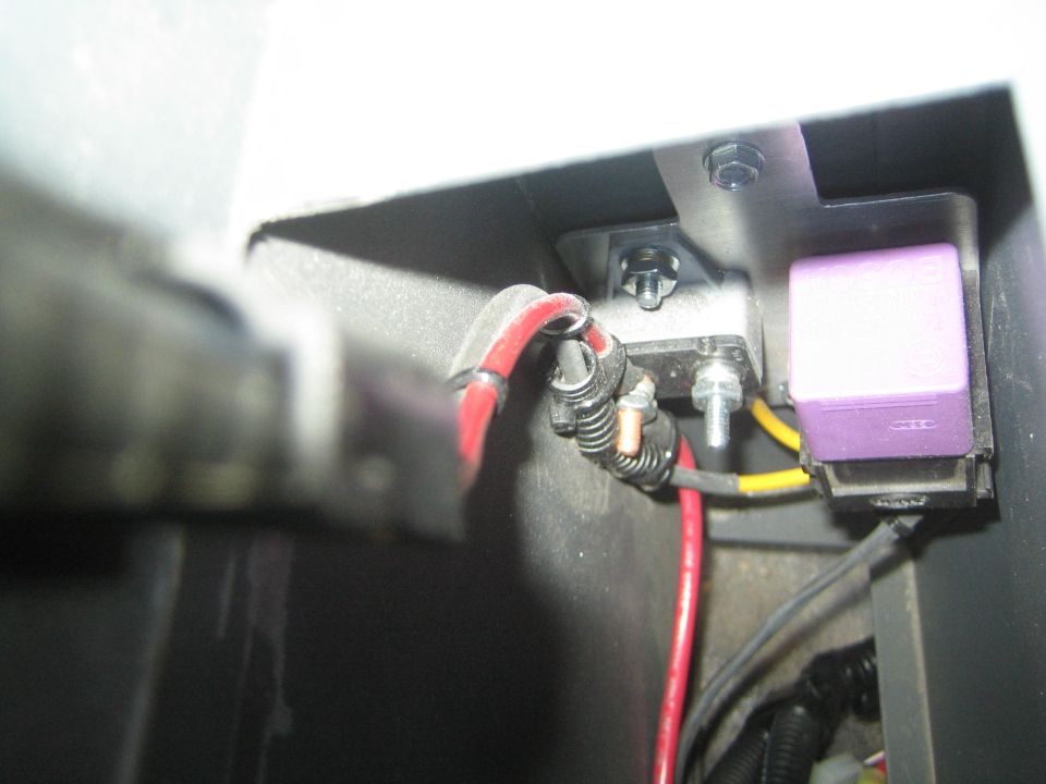 Wiring with red and yellow cables and a purple relay in a black compartment
