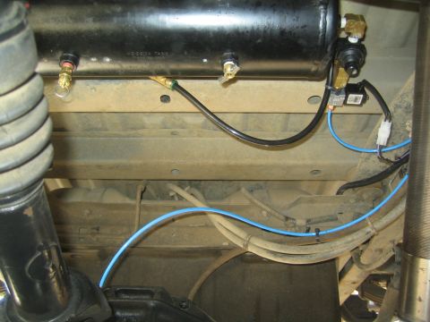 1990 Ford Bronco - black cylindrical air tank mounted under a vehicle chassis with brass fittings and blue and black air lines.