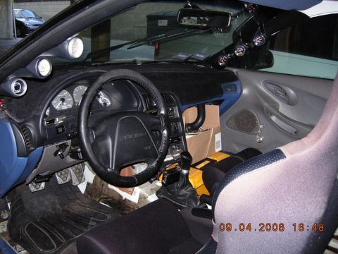 1993 Ford Probe - The interior of a car is shown, a steering wheel, dashboard, and racing seat with aftermarket gauges.