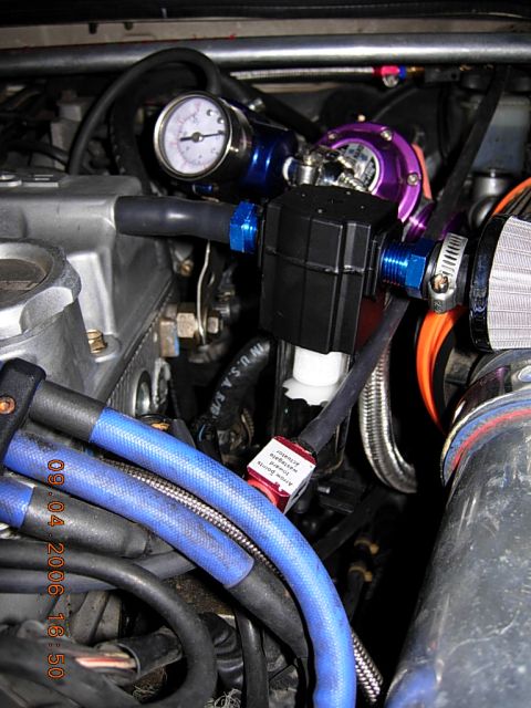 1993 Ford Probe - Close-up view of an engine bay a turbocharger, boost gauge, and various hoses. A red tag indicates the wastegate actuator.