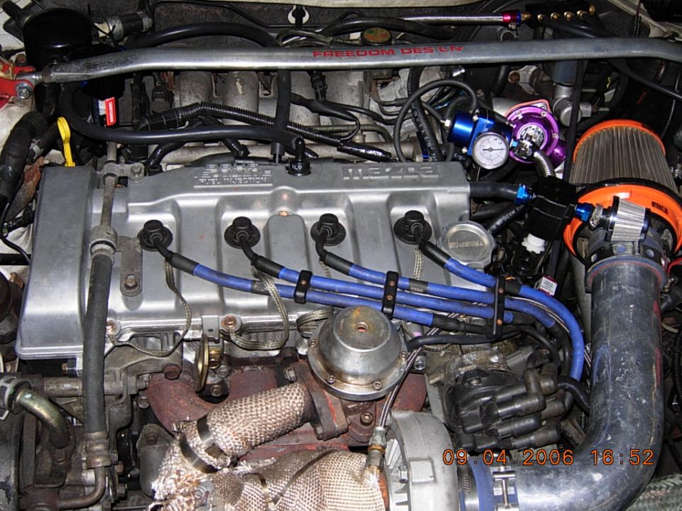 Turbocharged Mazda four-cylinder engine bay with blue plug wires and cone filter