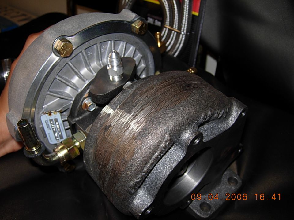 Turbocharger with aluminum compressor housing and dark cast iron turbine housing, held in hand