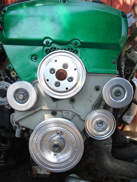 1993 Ford Taurus - Close-up of an engine assembly showing various pulleys and a green painted cover.