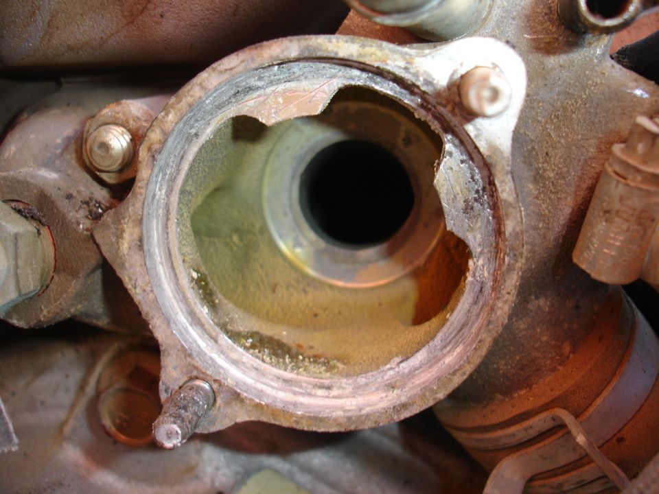 Close-up of a corroded engine part with a broken flange