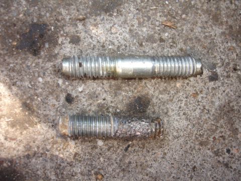 1993 Ford Taurus - Two metal studs, one showing corrosion, are placed on a concrete ground.
