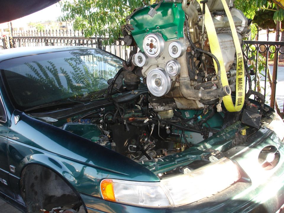 Green 1993 Ford Taurus with engine being lifted out