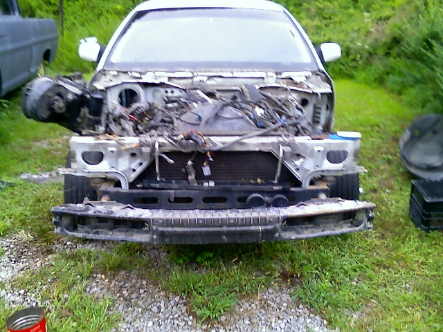White 2002 Ford Crown Victoria front end disassembled, showing exposed engine components and wiring