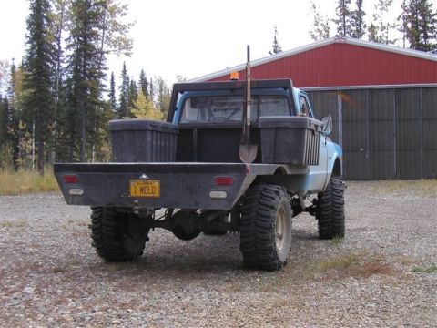1976 Ford F-150 - This modified truck features a flatbed, large off-road tires, and a shovel mounted in the bed.