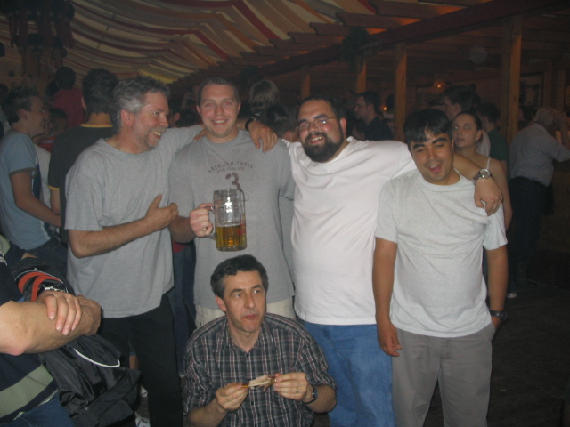 Group of men posing for a photo, one holding a beer mug