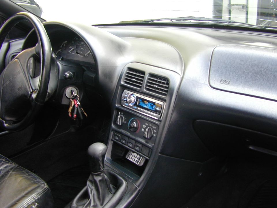 Black car interior dash with aftermarket head unit, manual shifter and SRS passenger airbag