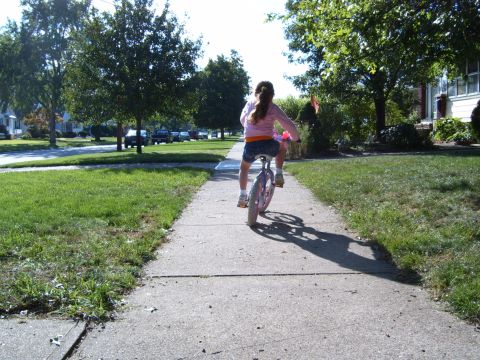 1993 Ford Bronco - A young girl rides a unicycle down a suburban sidewalk on a sunny day.
