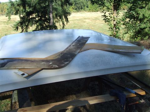 1979 Ford Bronco - Detached trim pieces rest on the roof of a white vehicle outdoors.
