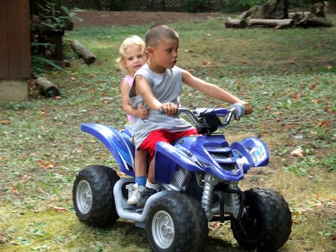 1976 Ford F-150 - Two children enjoy a ride on a blue ATV in a grassy, wooded area.