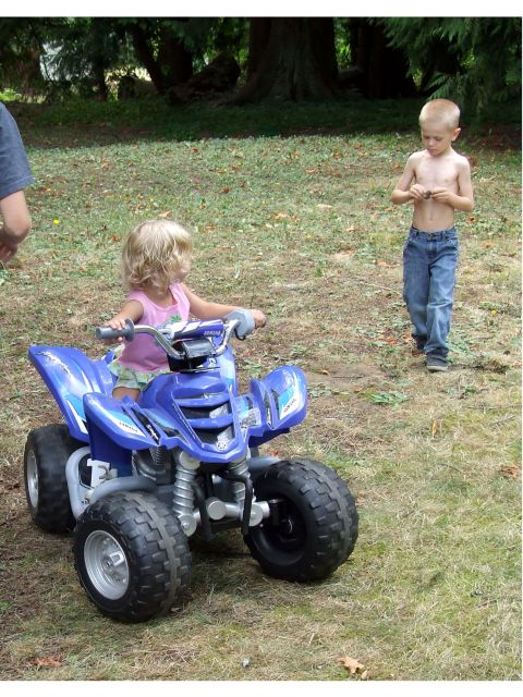 1976 Ford F-150 - A young girl rides a blue toy ATV while a boy watches in a grassy outdoor setting.