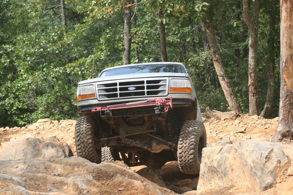 Silver Ford Bronco with large tires navigating rocky terrain, front view