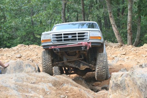 1990 Ford Bronco - This lifted Ford Bronco tackles a challenging off-road course, demonstrating its capabilities.