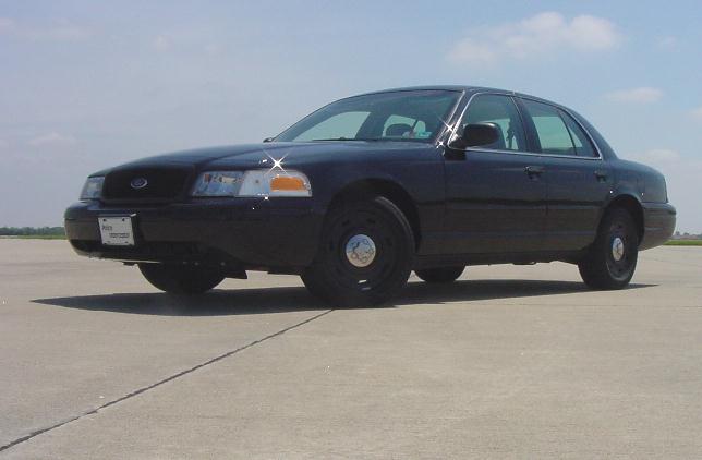 Black Ford Crown Victoria sedan with steel wheels parked on tarmac