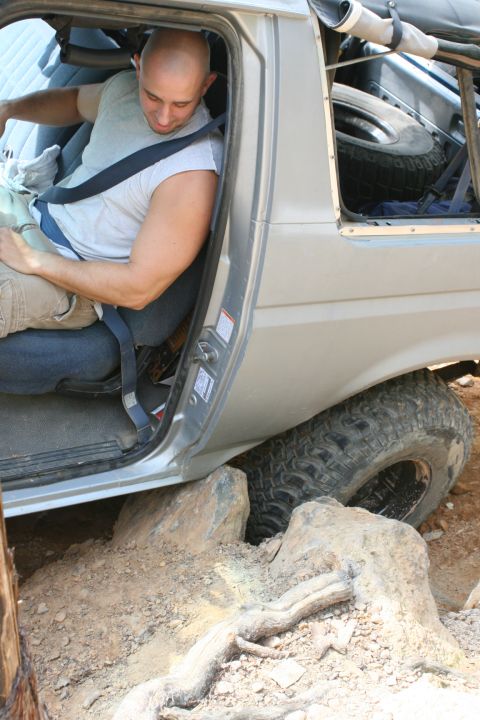 1990 Ford Bronco - Driver buckles up inside a 1990 Ford Bronco navigating rocky terrain.