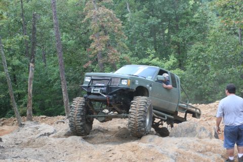 1990 Ford Bronco - A heavily modified pickup truck tackles a challenging off-road course with large tires and a lifted suspension.