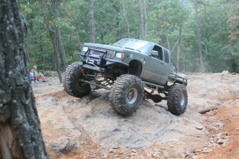 1990 Ford Bronco - This heavily modified truck navigates a rocky trail with significant suspension articulation.