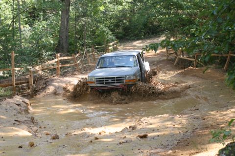 1990 Ford Bronco - A Ford Bronco navigates a challenging muddy obstacle course.