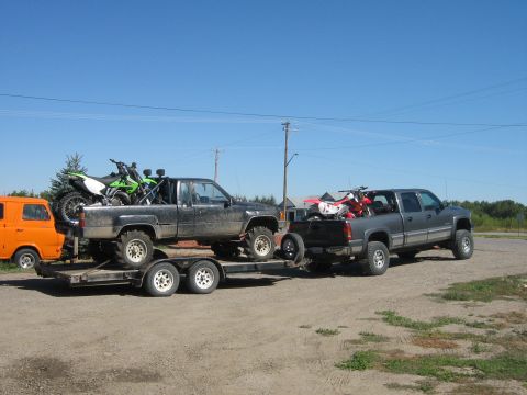 1995 Ford Bronco - Two trucks and a van are parked outside, with dirt bikes loaded onto the trucks.