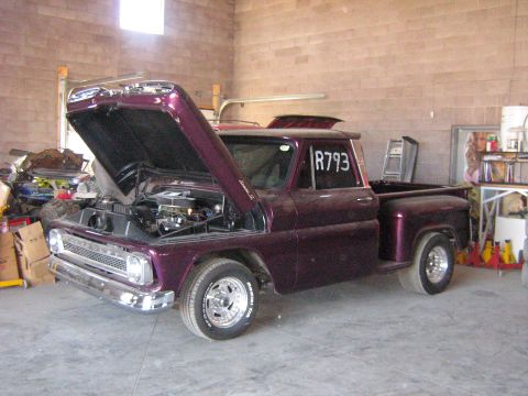 1995 Ford Bronco - A custom purple pickup truck is parked inside a garage with its hood open.