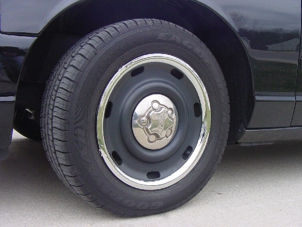 Gray steel wheel with chrome trim ring and Goodyear Eagle LS tire on dark vehicle