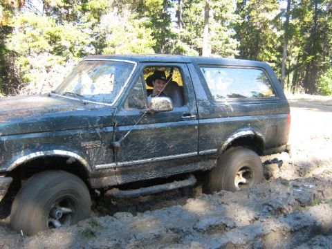 1995 Ford Bronco - A Ford Bronco is stuck deep in the mud off-road.