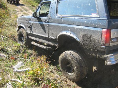1995 Ford Bronco - This 1995 Ford Bronco is shown in a 3q-front view, navigating an off-road trail covered in mud.