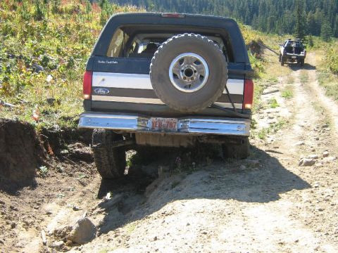 1995 Ford Bronco - 1995 Ford Bronco navigating a rough off-road trail with a second vehicle in the distance.