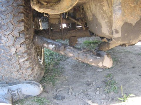1995 Ford Bronco - The undercarriage of a heavily soiled vehicle shows a large tire and exhaust system.