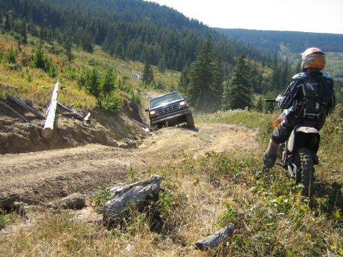 1995 Ford Bronco - A 1995 Ford Bronco navigates a steep, rutted trail while a dirt bike rider observes.