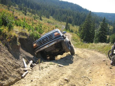 1995 Ford Bronco - A Ford Bronco navigates a steep, off-road incline, with one side dipping into a trench.