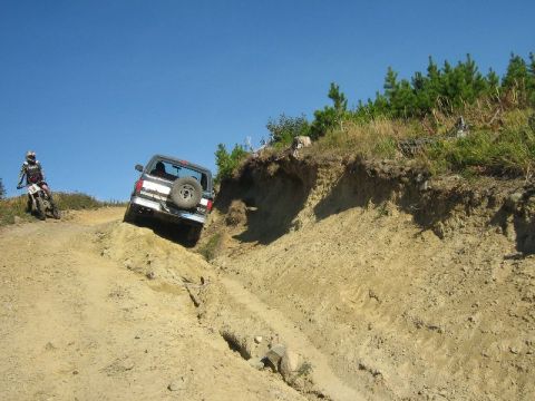 1995 Ford Bronco - Off-roading scene with a 1995 Ford Bronco and a dirt bike on a steep, dusty trail.