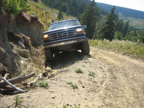 1995 Ford Bronco - A 1995 Ford Bronco navigates a challenging off-road trail with steep inclines and loose dirt.