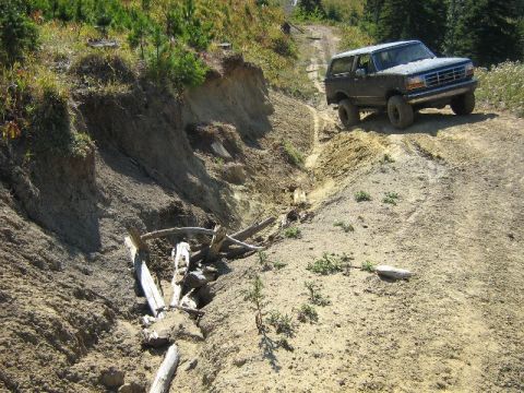 1995 Ford Bronco - Ford Bronco navigates a challenging off-road trail with steep inclines and eroded terrain.