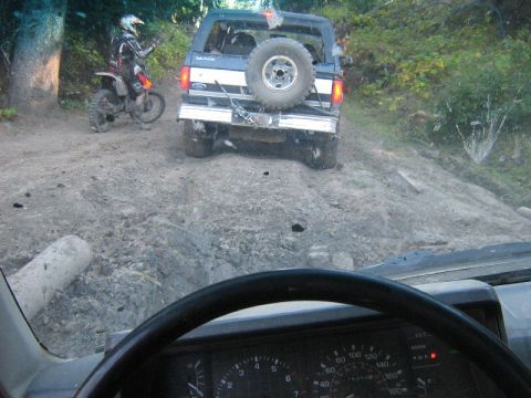 1995 Ford Bronco - Driving a 1995 Ford Bronco off-road with a dirt bike rider nearby.