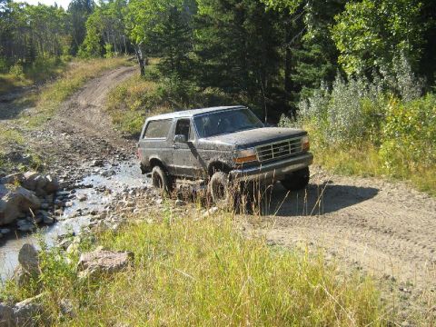 1995 Ford Bronco - Ford Bronco navigates a challenging off-road course with water and mud.