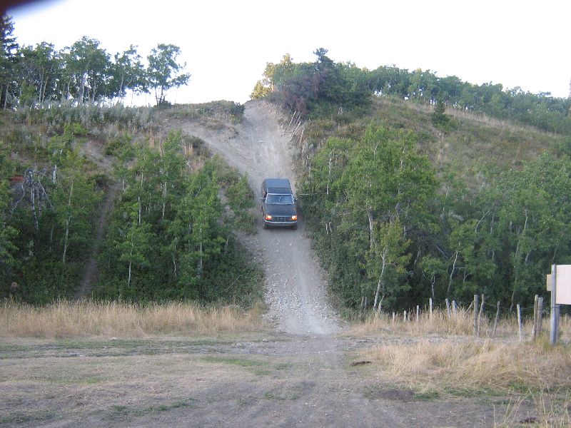 Dark 1995 Ford Bronco driving up a dirt hill