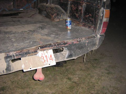 1995 Ford Bronco - A can of beer rests on the muddy tailgate of a pickup truck, with a pair of truck nuts dangling from the rear bumper.