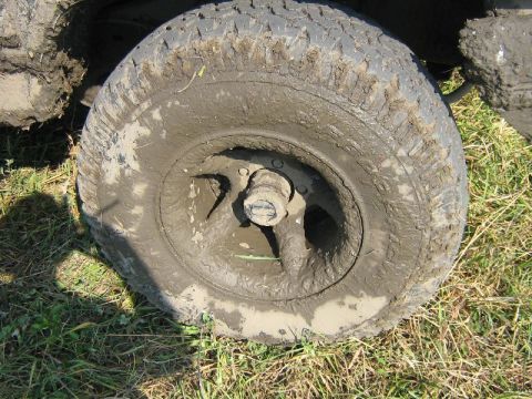 1995 Ford Bronco - A close-up view of a heavily mud-covered tire and wheel, suggesting off-road use.