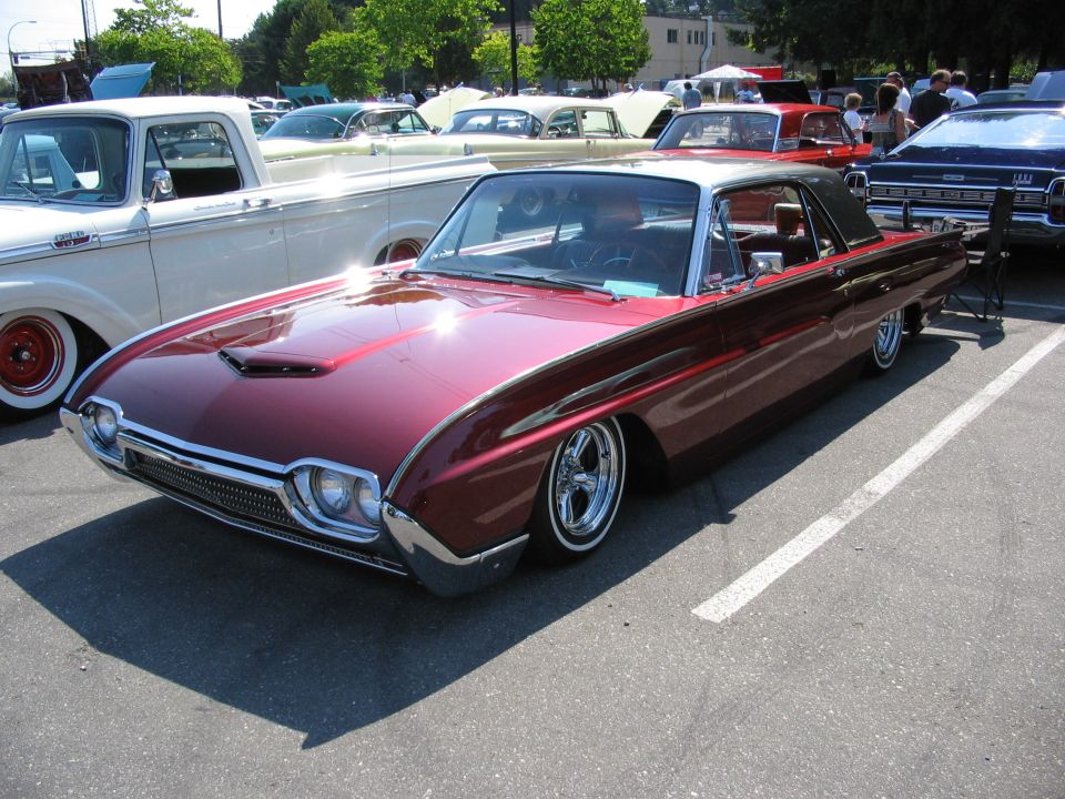 Lowered burgundy early-60s Ford Thunderbird hardtop with hood scoop at a car show