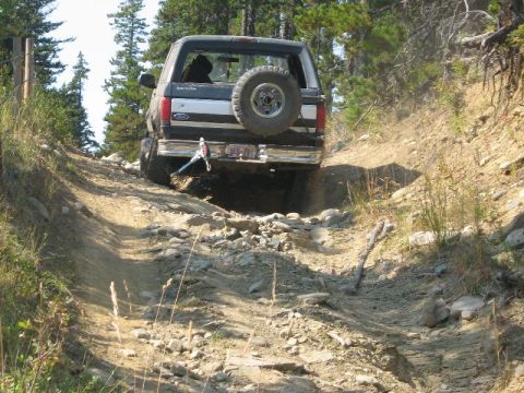 1995 Ford Bronco - This 1995 Ford Bronco is tackling a challenging off-road path, demonstrating its capability on rough terrain.
